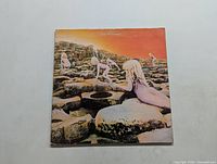 Front cover of the Led Zeppelin Houses of the Holy LP showing children climbing on rocks with vivid orange sky background