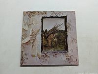 Front cover of Led Zeppelin IV album with iconic 'Hermit' artwork showing a man carrying sticks against a rustic wallpaper background. Shows wear and some discoloration.