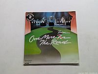 Front cover of Lynyrd Skynyrd double vinyl album 'One More From The Road' showing the band's name, album title and stage instruments with a winding road graphic.