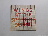 Front cover of the vinyl album with "Wings at the Speed of Sound" title text on a grid background.