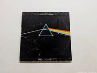 Front cover of The Dark Side of the Moon vinyl album with the iconic prism and light spectrum artwork. Shows wear and tear.