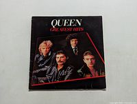 Front album cover showing Queen band members and title Greatest Hits with some wear.