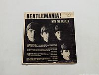 Front cover of the Beatles 'Beatlemania! With The Beatles' LP album showing black and white images of the band members and album title.