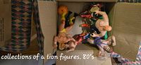 Box containing nine male wrestler and muscle-bound action figures from the 1980s, some of which have painted wrestling attire and boots.