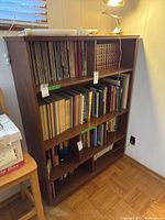 Front view of wooden bookcase with books on shelves, showing size and condition.