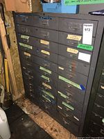 Full frontal view of the black metal 16-drawer cabinet in a shed.