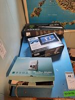 Overview of three retail boxes: Avision MiWand 2 Wi-Fi scanner, Fluid 7-inch Slim Digital Photo Frame, and Canon PowerShot SD450 camera on a table.