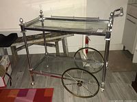 Full view of two-tier chrome and brass cart on wooden floor