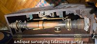 Brass telescope assembly inside wooden hinged case, showing focusing mechanism, eyepiece, objective lens and mounting rings.