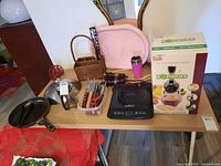 Full table view of all kitchenware items including boxes, utensils, pans, and small appliances