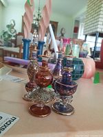 Photo showing four decorative glass perfume bottles together on a table, featuring different colors and designs.