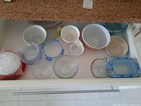 Drawers and countertop with Pyrex bowls and glass food storage containers arranged to display all pieces.
