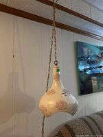 Swag lamp with ceramic floral shade, close detail visible, hanging on chain from ceiling
