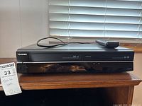 Front view of Toshiba DVR 620KC device with remote placed on top, showing Toshiba branding and operational indicators.