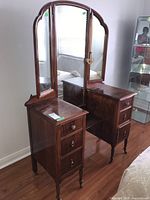 Front view of the wooden vanity showing six drawers and tri-fold mirrors with curved tops.
