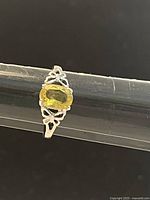 Front view of the 925 silver ring set with a bright yellow oval citrine gemstone, showing the ornate openwork detail on the band.