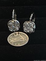 Pair of silver earrings with large square-cut clear Swarovski crystals and smaller crystals on hooks next to a Canadian quarter for size reference.