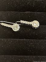 Pair of earrings laid flat in jewelry holder showing large round clear Swarovski crystal and line of smaller crystals on sterling silver.