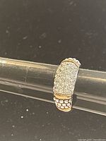 Angle showing cluster of clear Swarovski crystals on top half of silver ring band with textured bead-like detailing and gold-tone trims