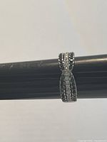 Ring displayed on a black ring sizing stick showing its bow shape and crystal detailing.
