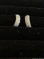 Pair of half hoop earrings encrusted with small Swarovski crystals against a black velvet background showing front view of sparkle and shape.