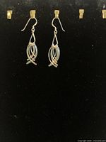 Pair of sterling silver earrings shaped like stylized fish on a black velvet display.