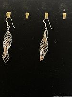 Pair of .925 sterling silver earrings hanging against black background showing full length and intricate design.