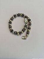 Silver-tone bead bracelet laid flat showing detailed beads and clasp.