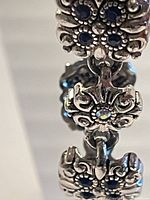 Close up of the flower-shaped links with blue rhinestones and ornate metal detailing on the bracelet.