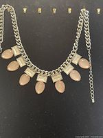 Full view of the necklace showing the alternating oval pink and rectangular white stones on a silver-tone heavy chain