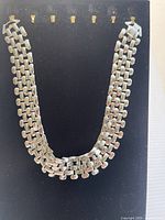 Front view of the gold plated multi-strand chain necklace displayed on a black stand.