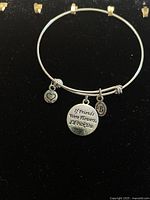 Silver-tone bangle bracelet with three charms on a black background