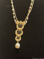 Close-up of the pendant showing the detailed Italian filigrana gold-tone metal work and single hanging faux pearl.