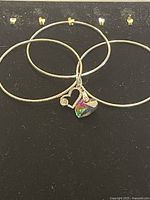 Set of three silver-tone bangles and two heart-shaped charms featuring rainbow-colored Swarovski crystal and clear stones.