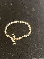 Photo of a tennis bracelet laid flat on a black textured surface showing the full bracelet and its clasp open.