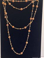 Full view of the long amber beads chain necklace laid out showing bead pattern and length