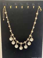 Full view of the vintage brass chain necklace with small and large clear crystal drops arranged along the chain and hanging as pendants.