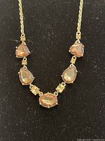 Close-up frontal image of the vintage-style necklace showing champagne-colored gemstones on gold-tone chain