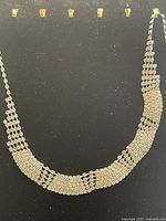 Full view of the vintage cluster rhinestone necklace displayed against a dark background, showing the overall shape and sparkle.