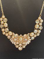 Front view of the necklace showing the symmetrical arrangement of pearls and crystals on a gold-tone metal base.