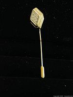Gold plated vintage stick pin brooch with cluster of crystals on hexagonal head, shown against a black background.