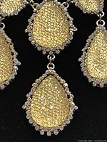 Close-up of a teardrop-shaped yellow crystal pendant surrounded by clear crystals on a silver-tone metal chain showing texture and sparkle.
