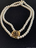 Full view of double-stranded white pearl chain necklace on black background