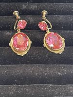 Front view of two pink crystal earrings with a screw-back clasp on black velvet background