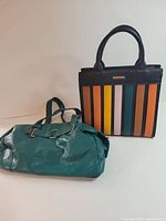 Two handbags side by side: striped Mia Luca and teal faux leather