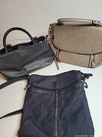 Three handbags laid out: Guess patterned, Aldo taupe, Denver Hayes navy