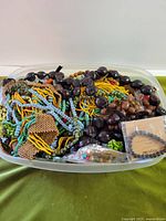 Large clear tub filled with mixed beaded necklaces