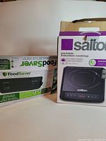 Cooktop and vacuum sealer boxes side by side
