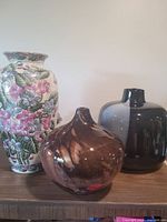 Group view of three vases on shelf
