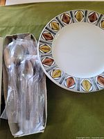 Dinner plate alongside boxed spoons in plastic sleeves